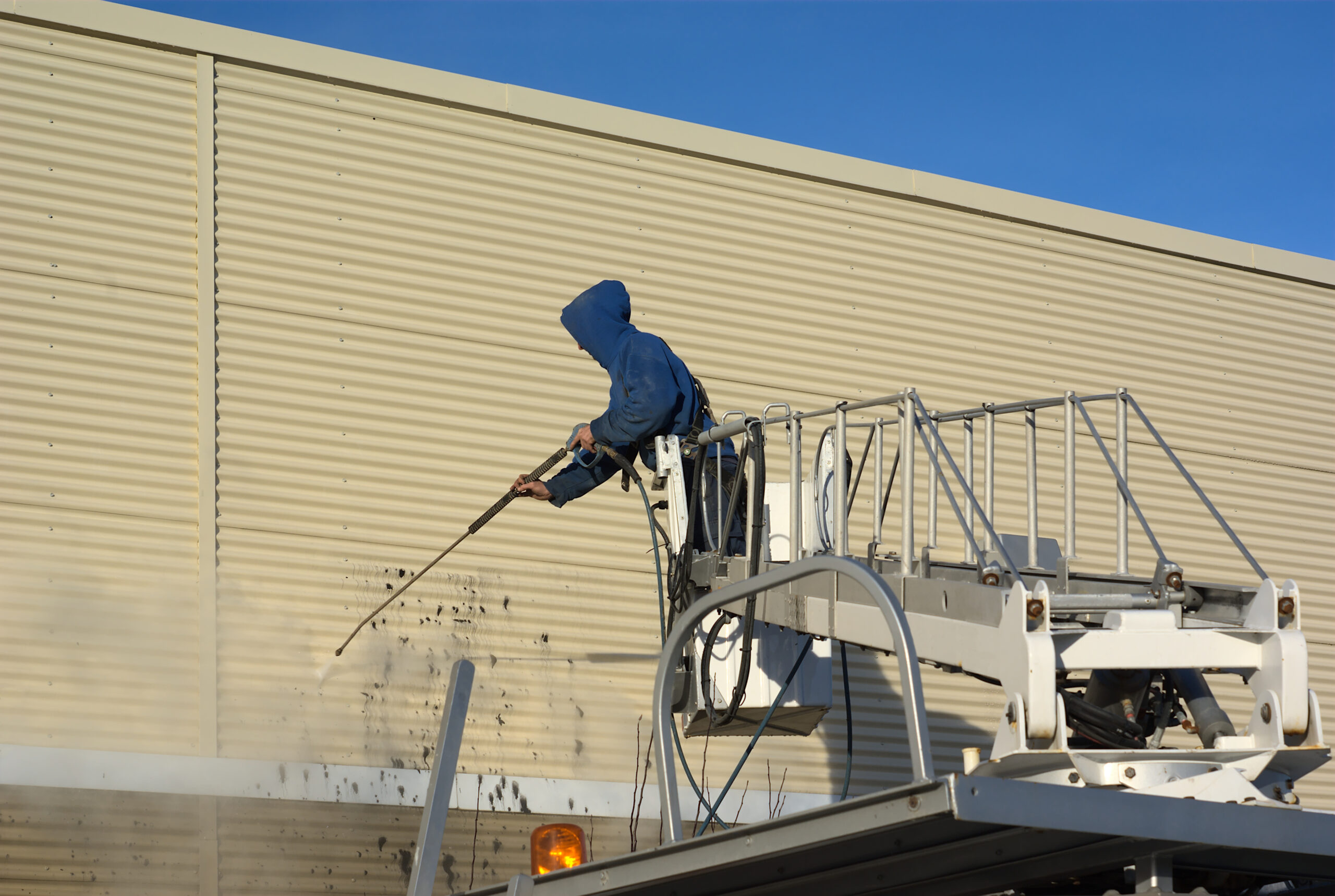 Professional power washing exterior of industrial building. 